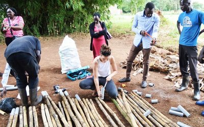 Menschen im ländlichen Setting bei der Bearbeitung von Bambusstämmen