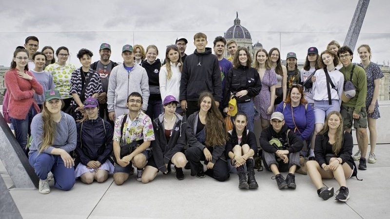 Eine Gruppe von über 30 jungen Menschen steht auf einer Aussichtsplattform, im Hintergrund sieht man das Naturhistorische Museum in Wien