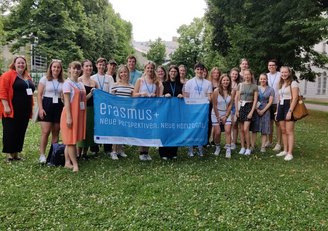 Gruppe junger Menschen hält Erasmus+ Banner in die Kamera 