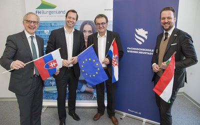 OeAD-Geschäftsführer Stefan Zotti mit drei Personen, die verschiedene Nationalflaggen in der Hand halten.