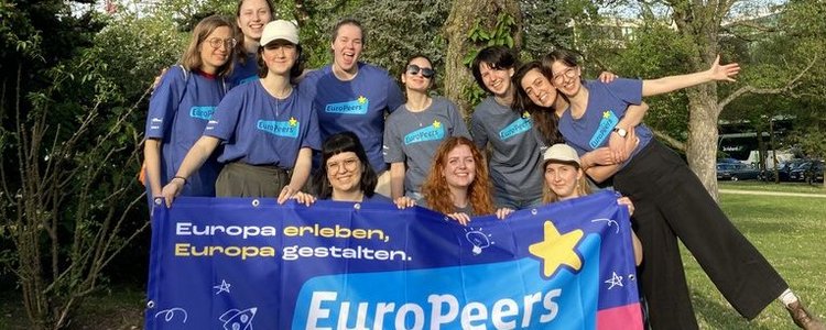 Gruppe junger Menschen hält EuroPeers Flagge in der Hand 