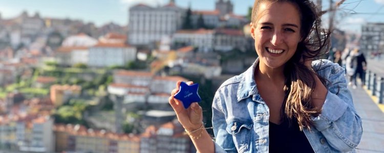 Eine junge rau steht auf einer Brücke in Porto und hält einen Stern ins Bild