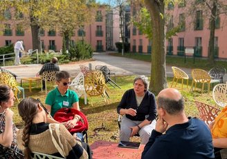 Foto von Personen im Sitzkreis, welche sich unterhalten