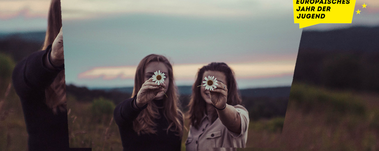 Zwei junge Frauen halten Gänseblümchen vor ihre Gesichter
