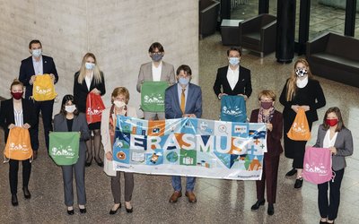 Gruppe mehrerer Menschen, die einen Erasmus-Banner in der Hand halten.