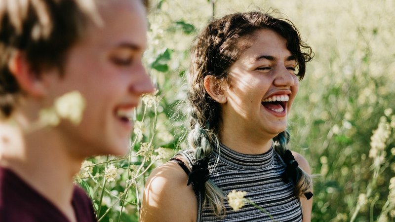 Zwei junge Frauen lachen und schauen in die Ferne