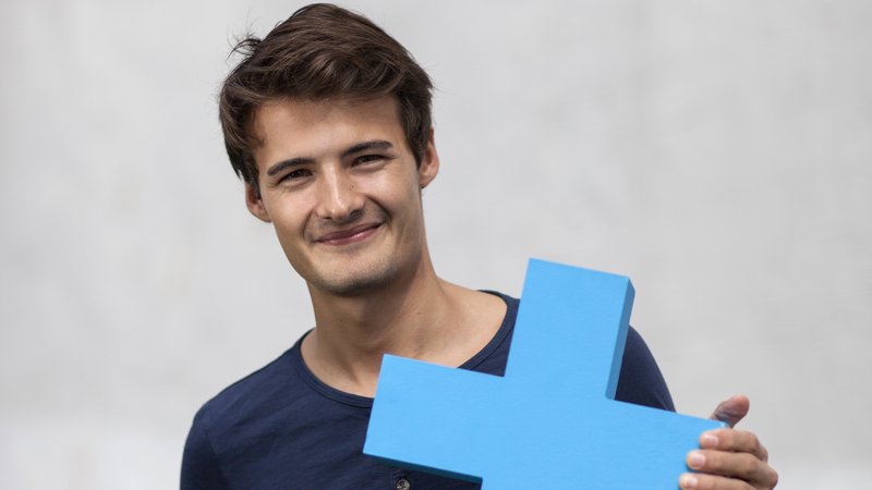 Junger Mann hält blaues Erasmus-Logo in die Kamera